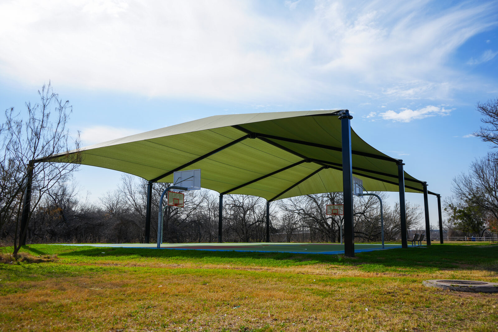 A shaded basketball court under a large fabric canopy at an Austin park