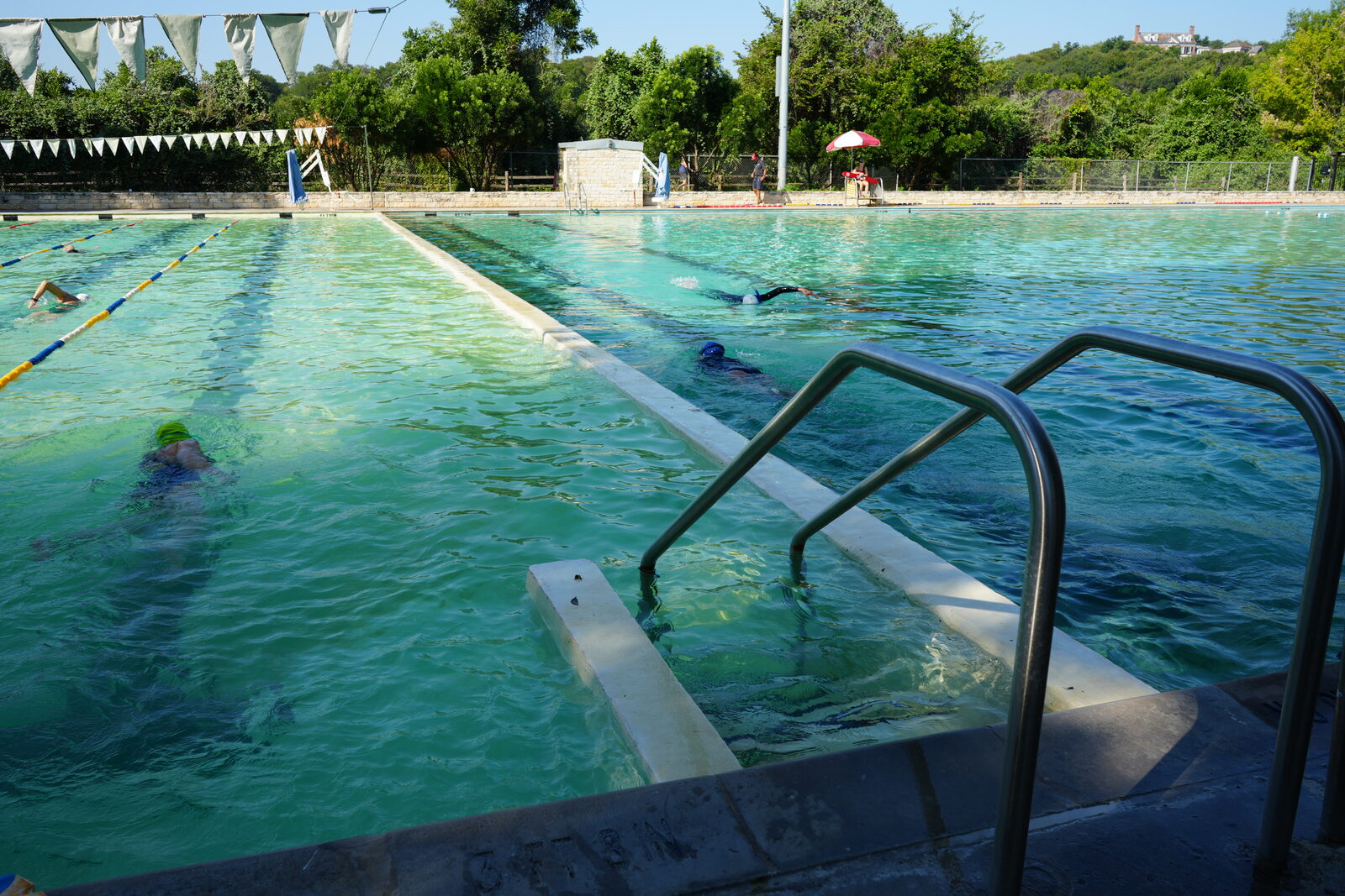 Swimmers doing laps in an outdoor municipal pool